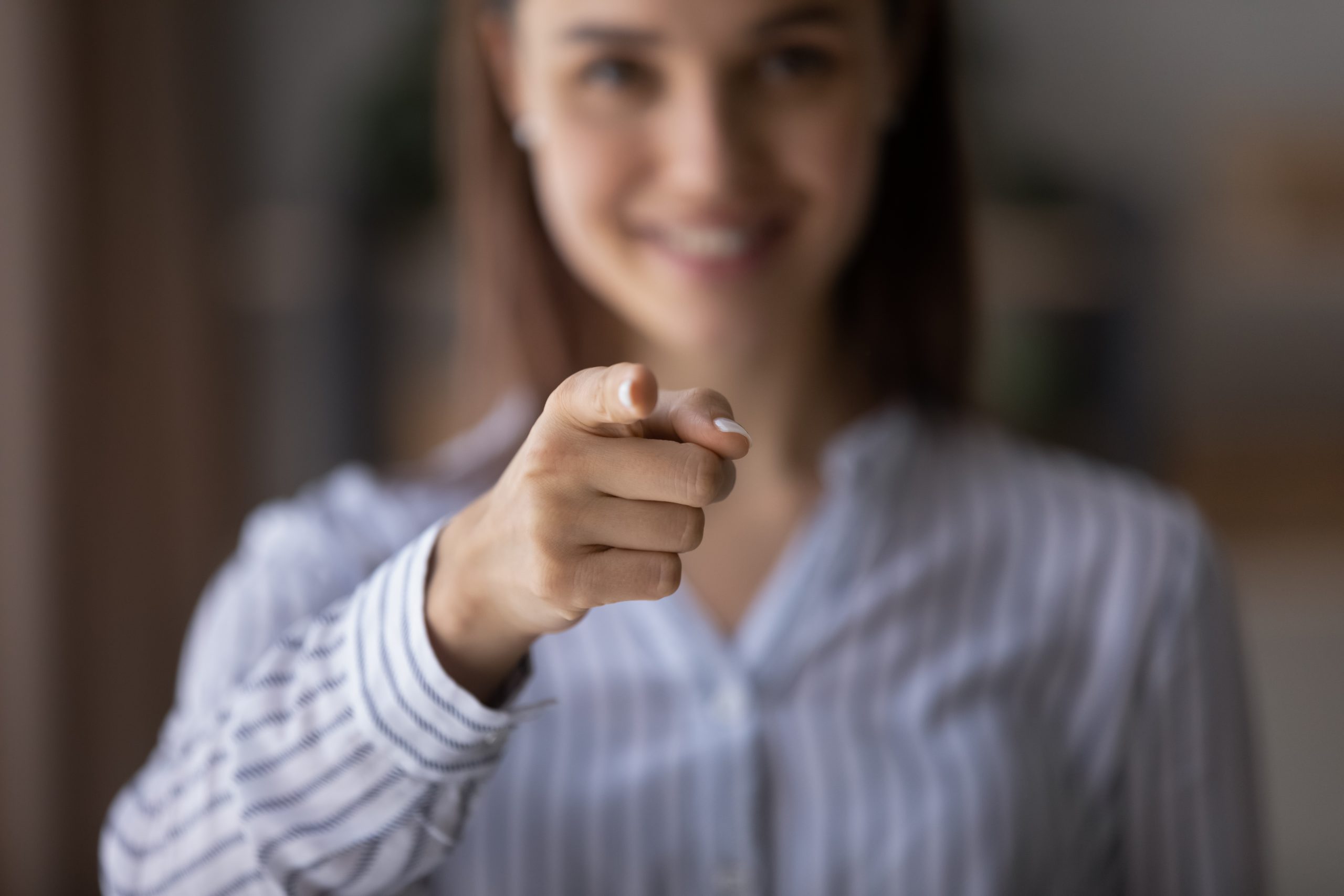 Happy,Blurred,Young,Woman,Pointing,Index,Finger,At,Camera,,Smiling.